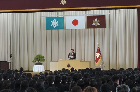 大勢の学生たちが座る会場で、舞台上の演台のマイクに向かい話をする市長の写真