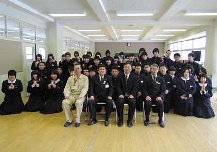 椅子に座った市長と3名の男性の後ろに並ぶ中学生たちの記念写真