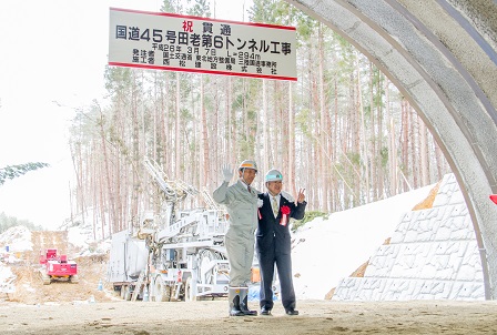 トンネルの入り口で、ヘルメットを被った男性と市長が肩を組み、ピースサインをしている記念写真