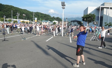 駐車場に集まった大勢の参加者と市長がラジオ体操をしている様子の写真