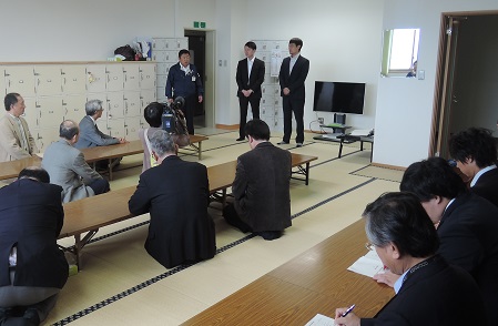 畳の部屋で長机の前に座る関係者の方々と、前方に立つ市長と2名のスーツを着た男性の写真