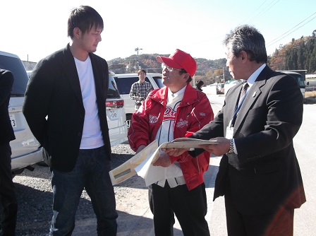 赤い帽子と上着を身に着けた市長と岩隈久志さんが話をしている様子の写真
