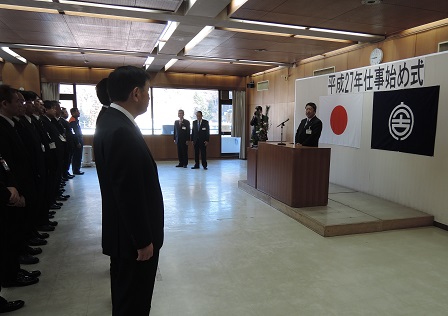 整列している市の職員の方々の前で、演台で市長が訓示を述べている写真