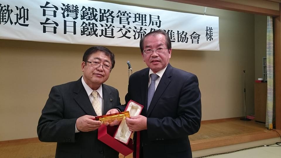 台湾鉄路管理局の鹿局長と市長が横に並び、赤い箱に入っていた金色の物を一緒に持っている写真