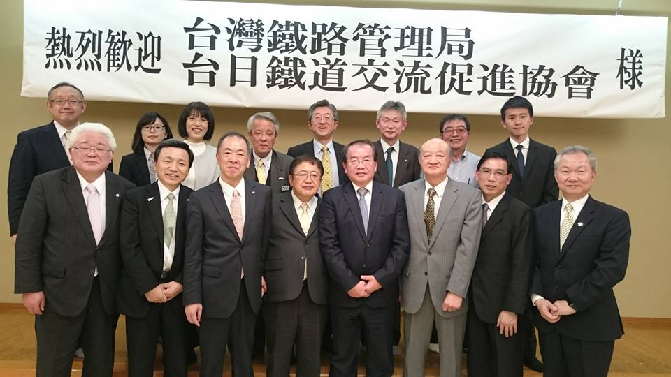 「熱烈歓迎 台湾鉄路管理局 台日鉄道交流促進協会様」と書かれた横断幕が貼られたステージに、市長を中央に鹿局長と14名の関係者が2列に並んでいる集合写真
