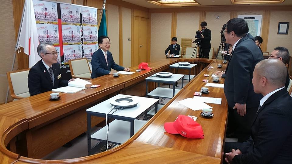 マスコミのカメラが撮影しているなか、左中央の席に座っている達増知事と、右側の席から立ち上がった市長が話をしている様子の写真