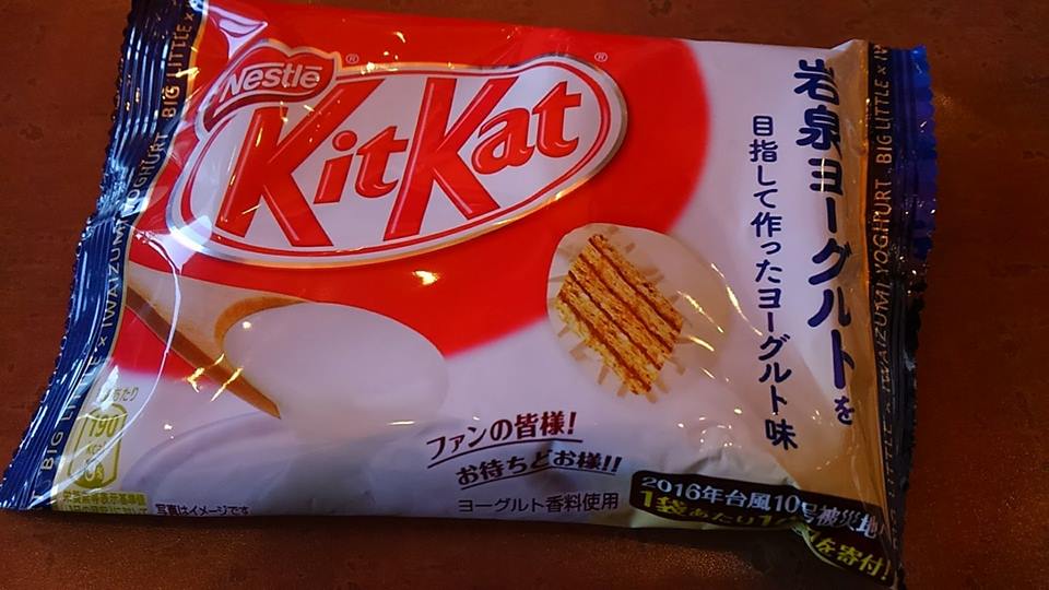 右側に青文字の縦書きで「岩泉ヨーグルトを目指して作ったヨーグルト味」と大きく書かれ、木製のスプーンですくったトロトロのヨーグルトとウエハースにヨーグルト風味のチョコレートがかかったキットカットの断面の写真が印刷されている、岩泉ヨーグルト味のキットカットの袋入りの商品パッケージの写真