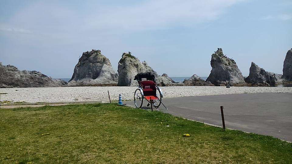 浄土ヶ浜をバックに、芝生広場とコンクリートの境目に人力車が置かれている写真