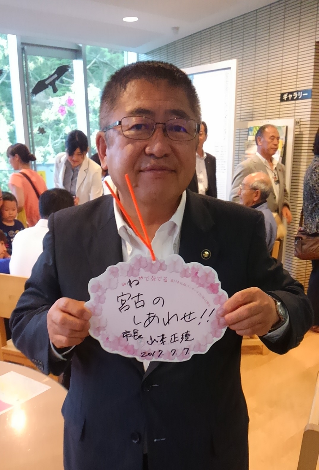 「宮古のしあわせ！！」と手書きで書いたプレートを両手で持つ市長の写真