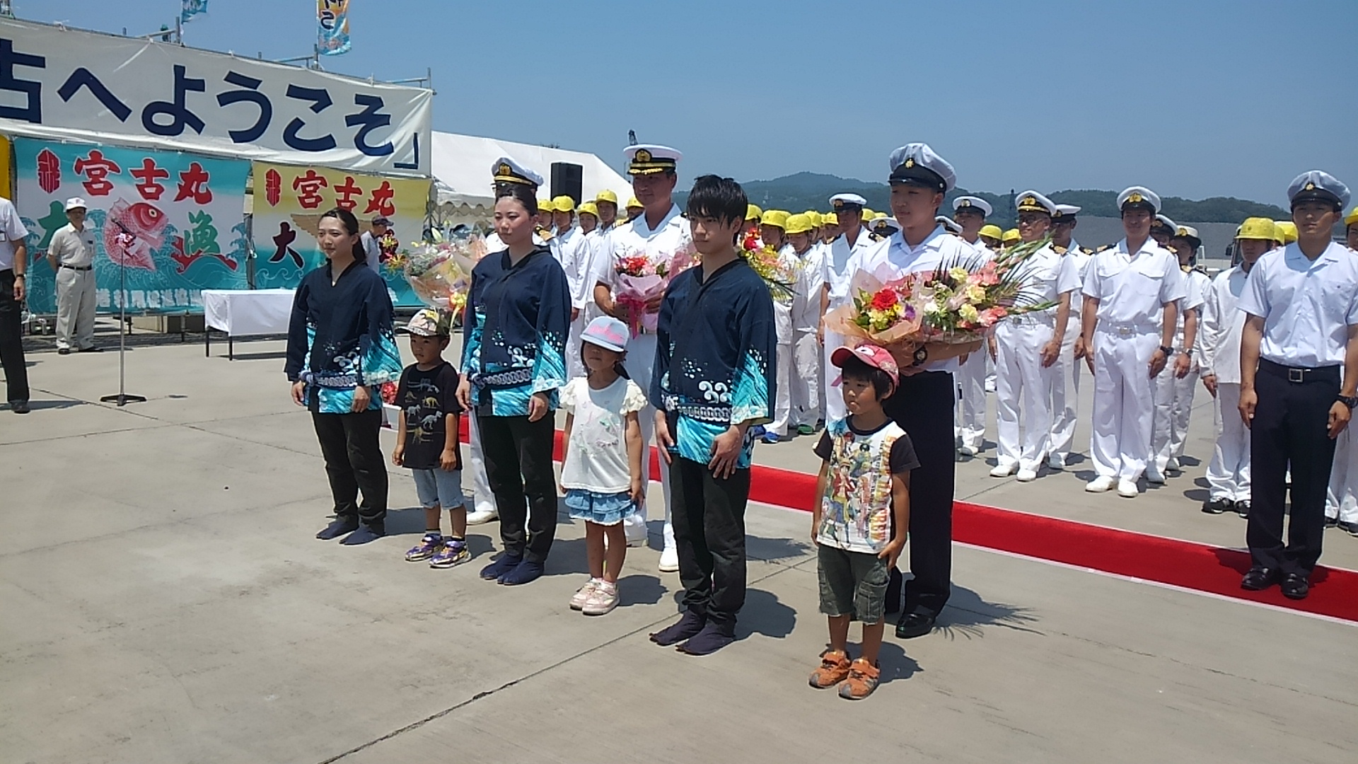 3名の法被を着た大人と3名の子供が交互に並び、後方に白の制帽、制服姿の海王丸の乗組員の方々が並んでいる写真