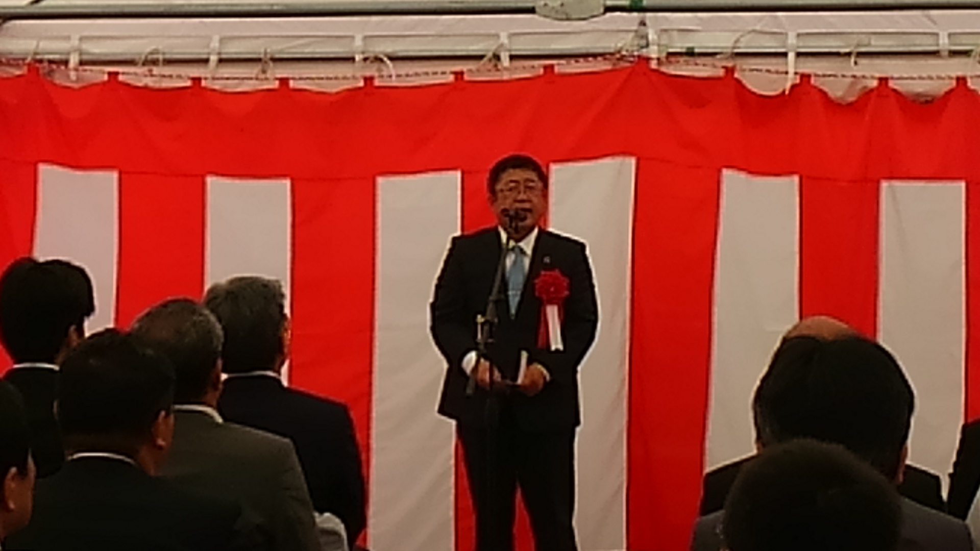 紅白幕の前でスタンドマイクに向かい話をする市長の写真