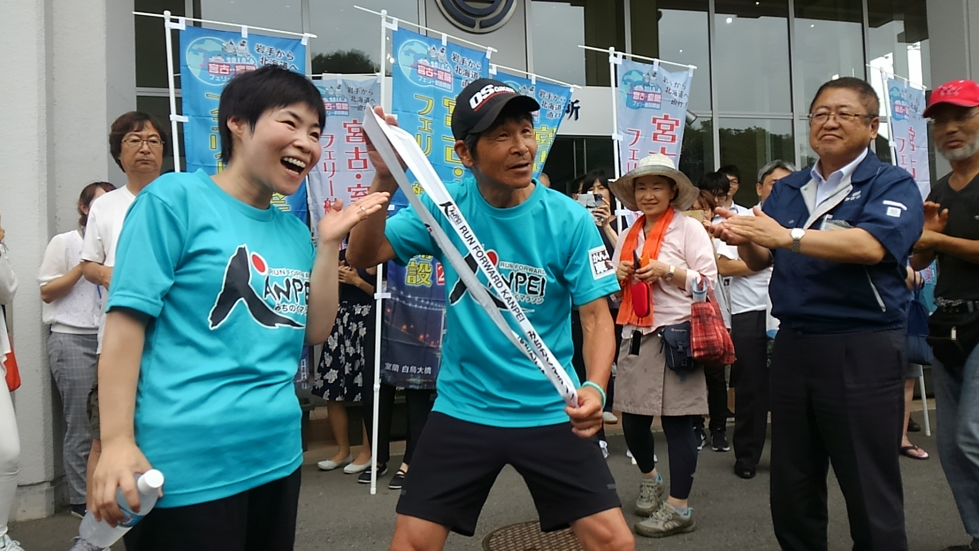 青色のTシャツを着た山田花子さんと間寛平さん、拍手をしている市長を写した写真