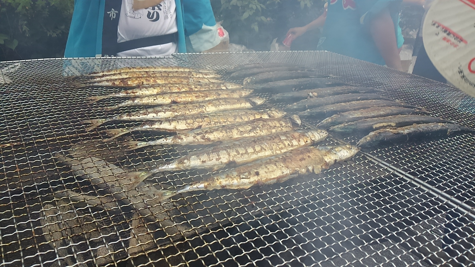 モクモクとした煙が出ている網の上に並んだサンマに焦げ目がついて食べ頃になった様子の写真