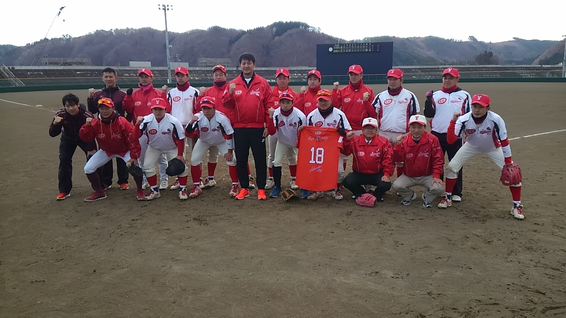 野球場で岩隈久志さんと市長、ユニフォームを着た小学生たちが2列に並んでいる記念写真