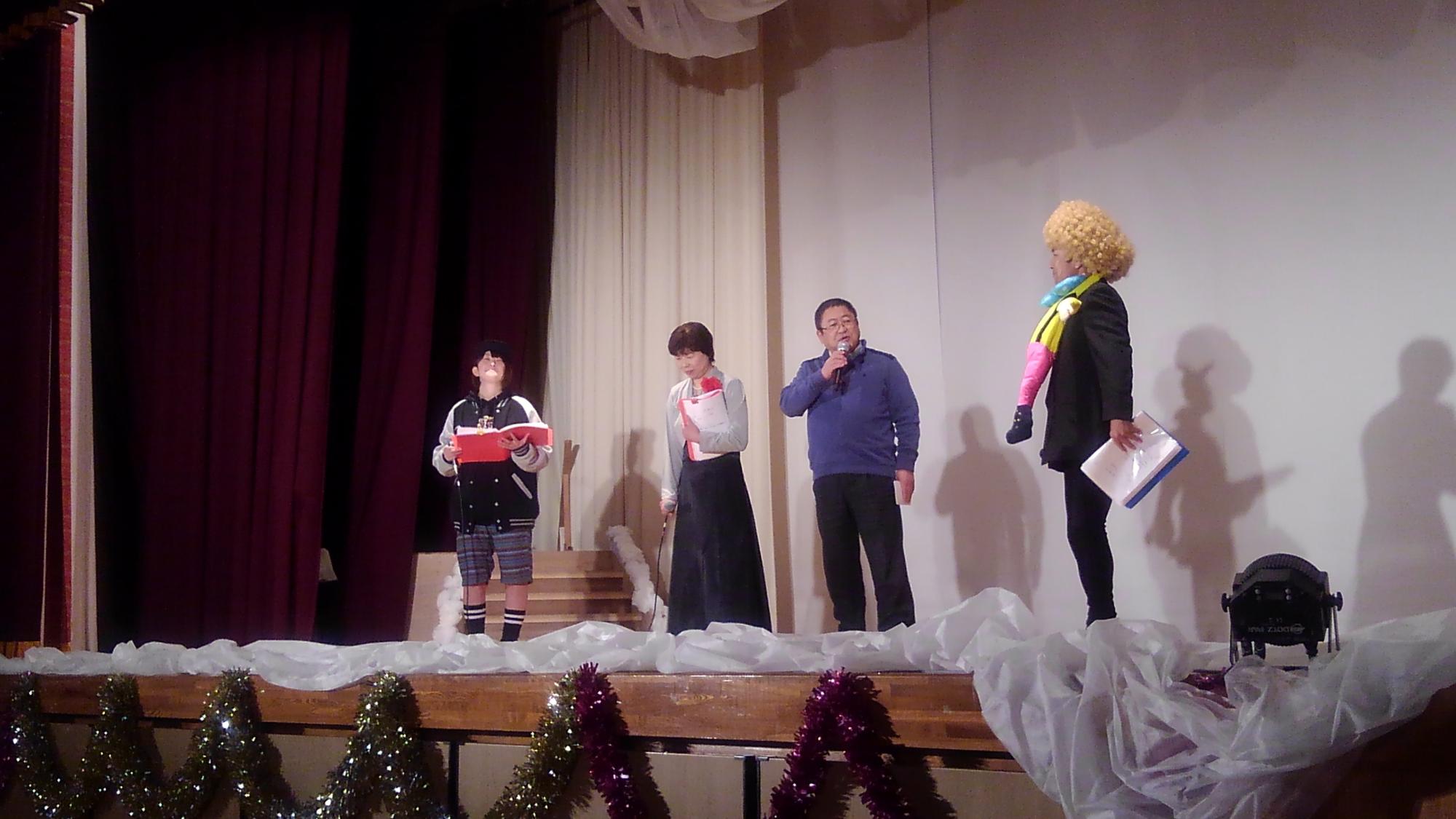 舞台の上に立つ市長と3名の方々の写真