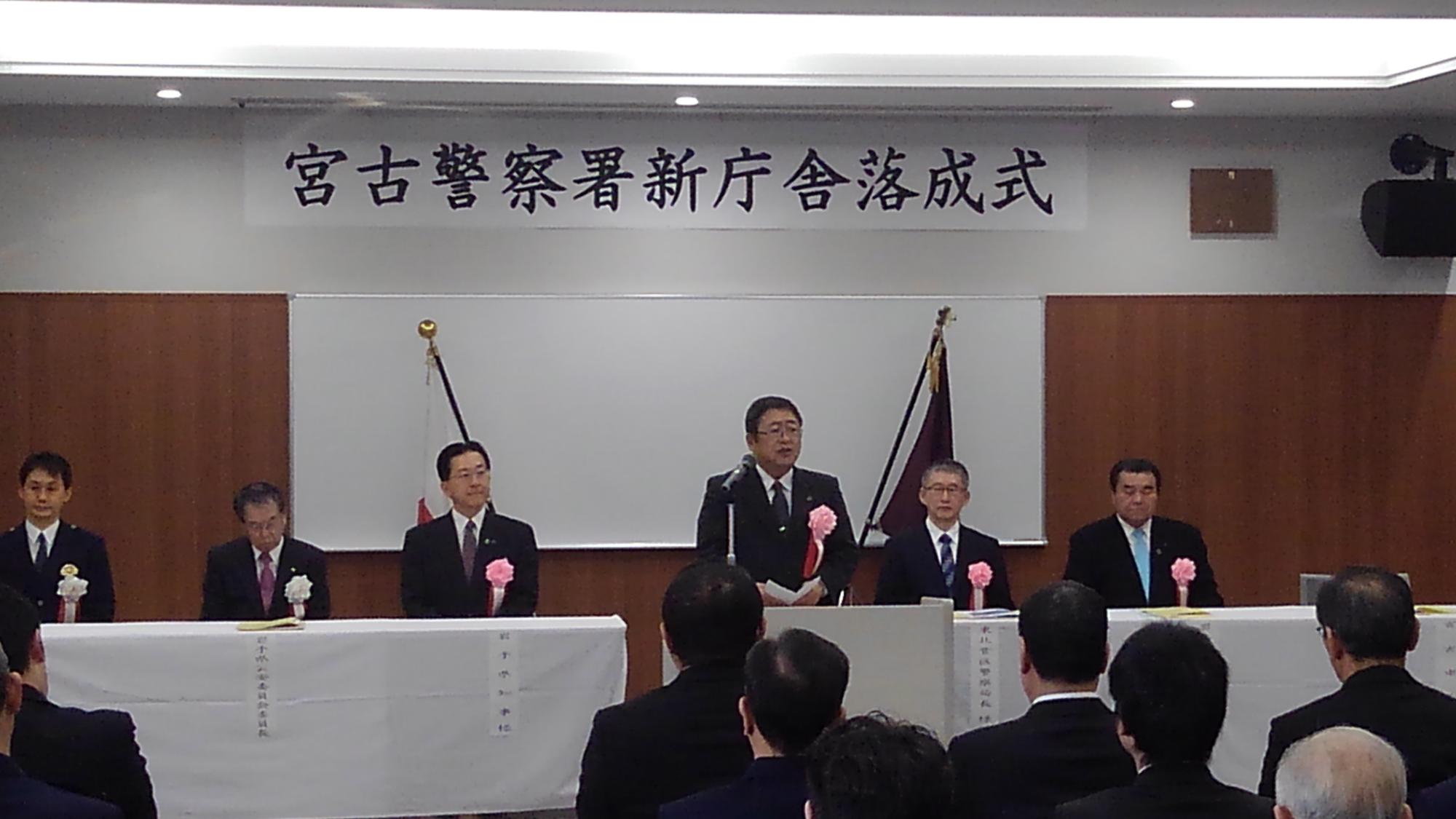「宮古警察署新庁舎落成式」と書かれた横断幕が吊るされた壁の前で、マイクに向かい話をする様子の市長の写真