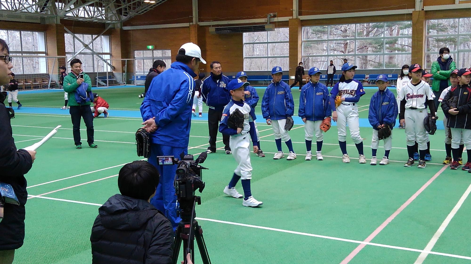 ユニフォームを着た少年野球の児童たちに指導する様子の青いジャージを着た福岡ソフトバンクホークスの工藤公康監督の写真