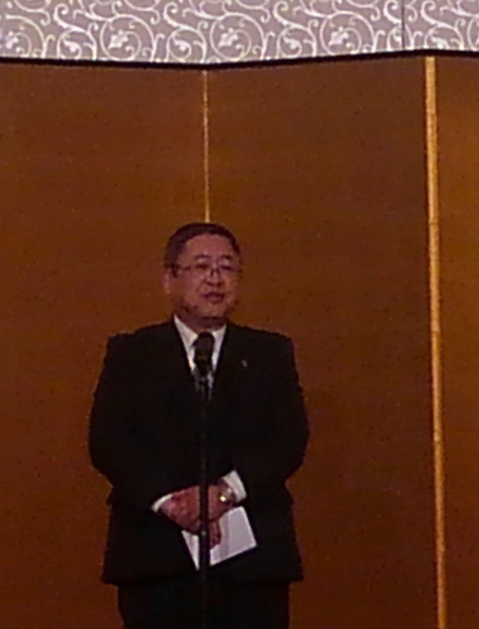 金屏風の前でスタンドマイクに向かい話をする様子の市長の写真