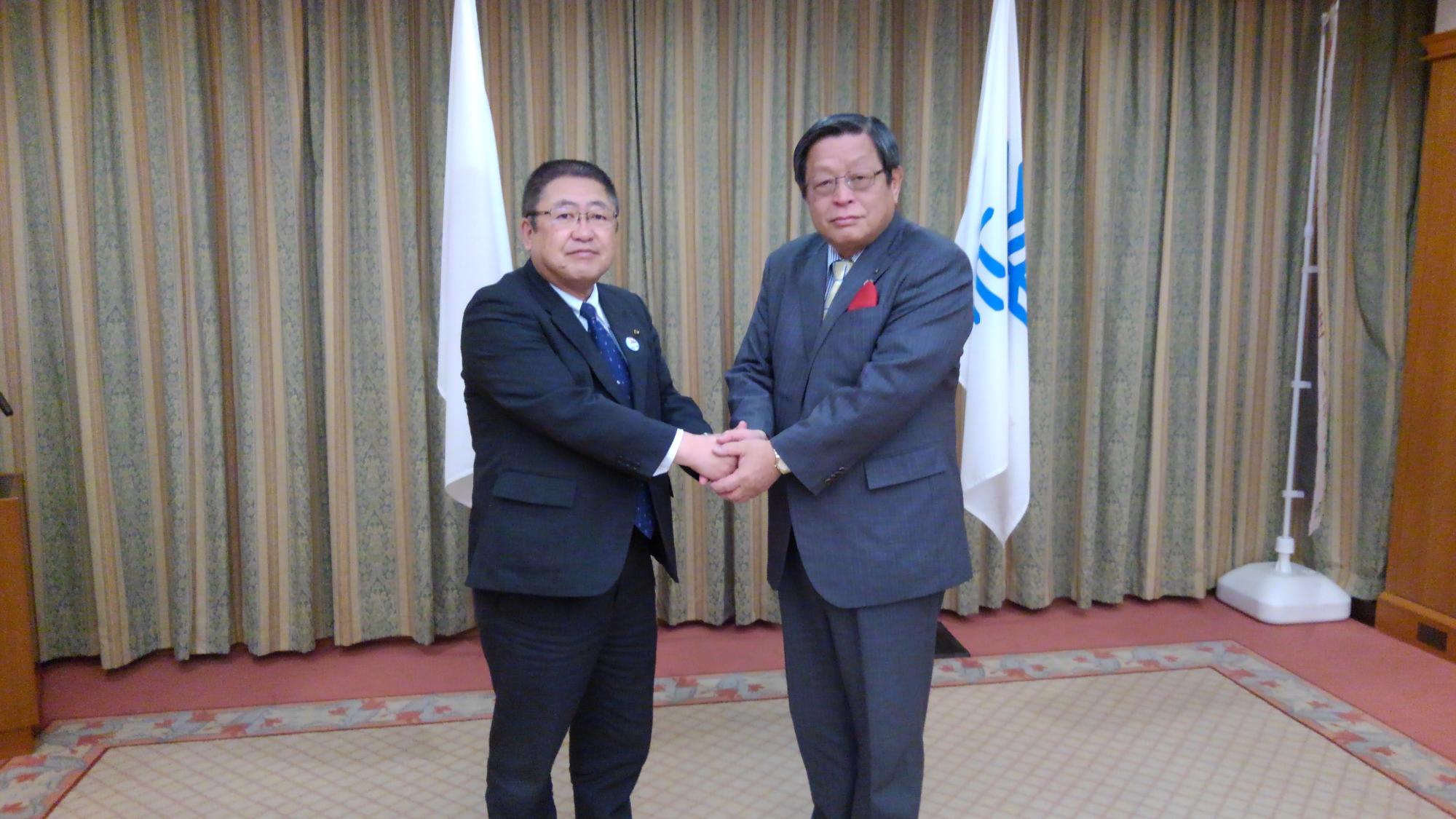 両手で握手をする市長と大阪府堺市・竹山修身市長の記念写真