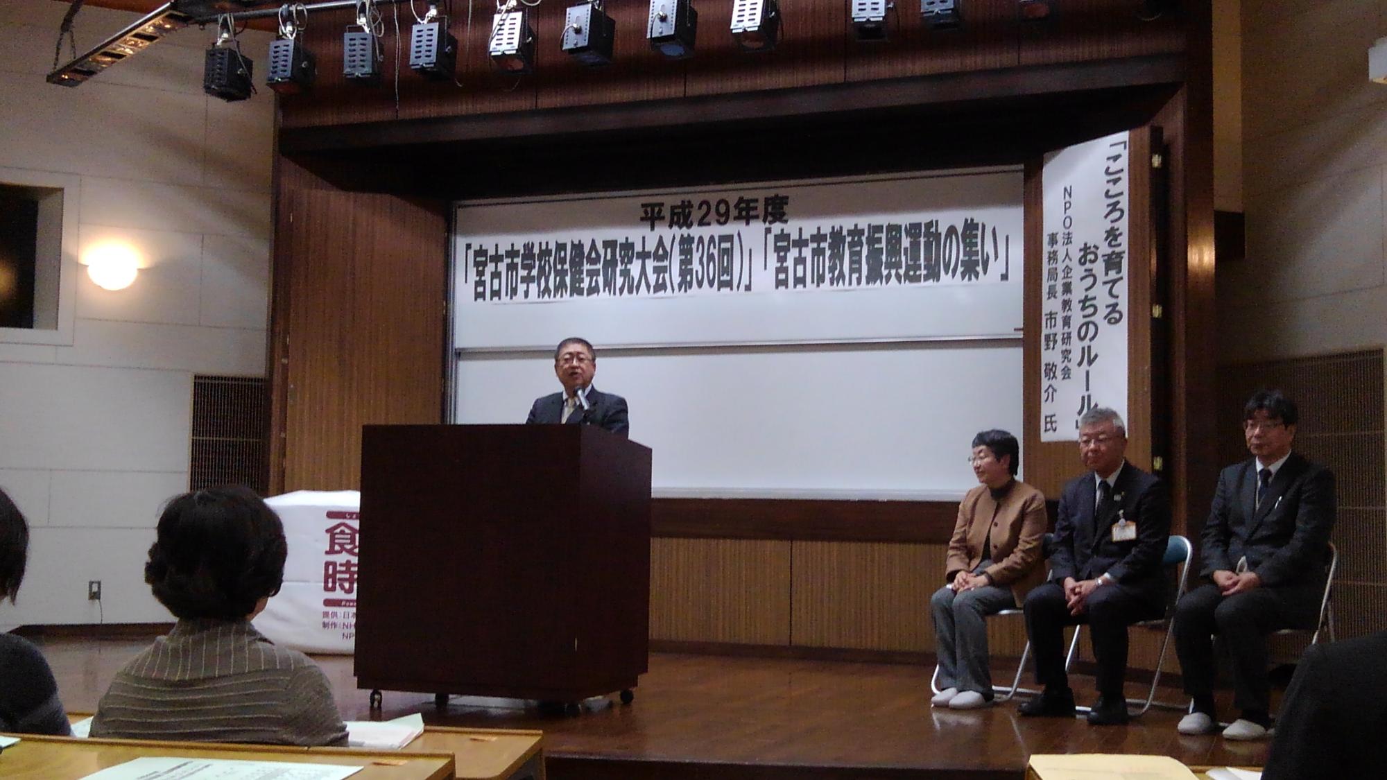 演台に置かれたスタンドマイクに向かい話をする様子の市長の写真