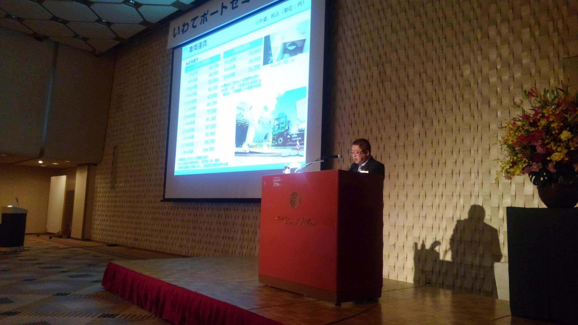 画面が映されたスクリーンの横の演台に置かれたマイクに向かい話をする様子の市長の写真