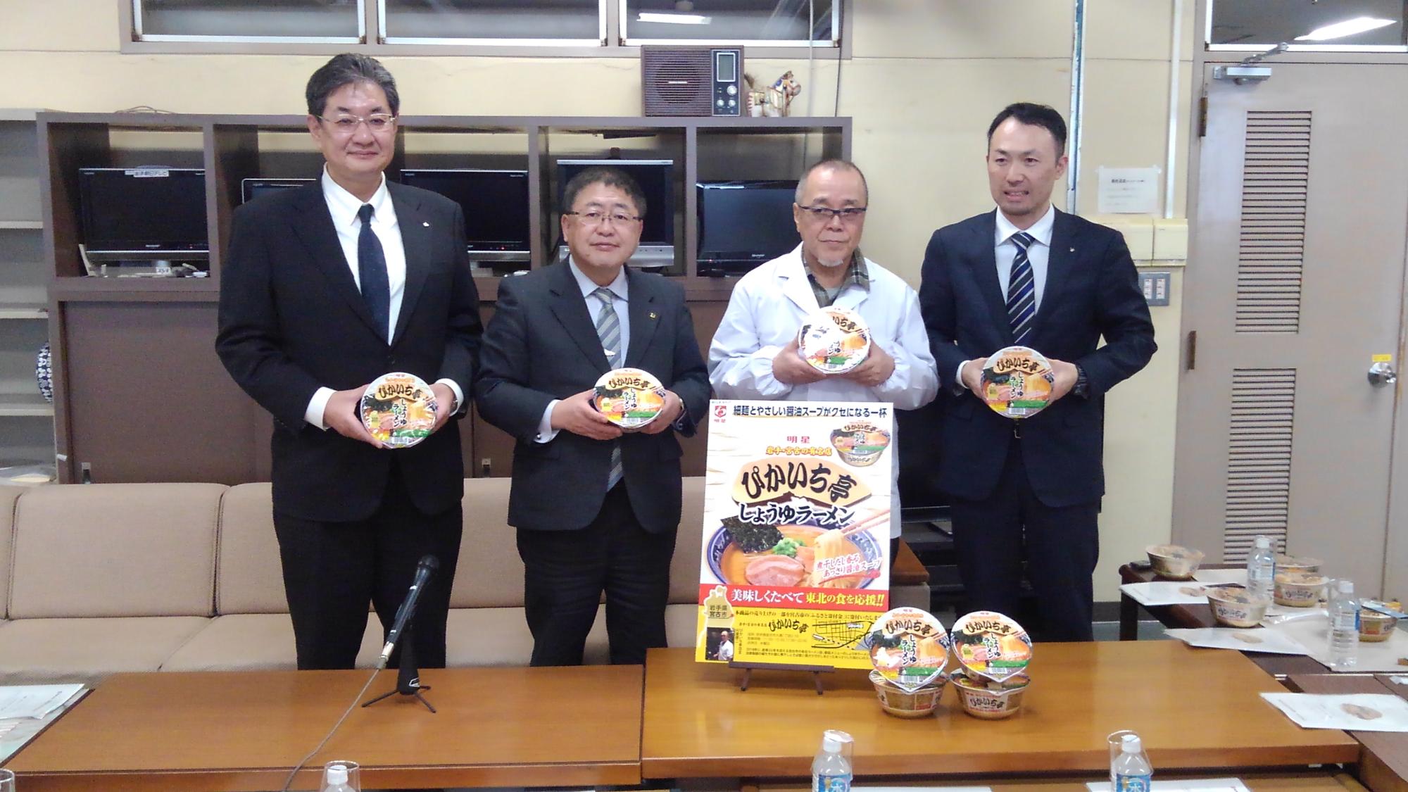 カップラーメンを持って蓋の部分を正面に向ける市長と3名の男性が横一列に並んでいる写真