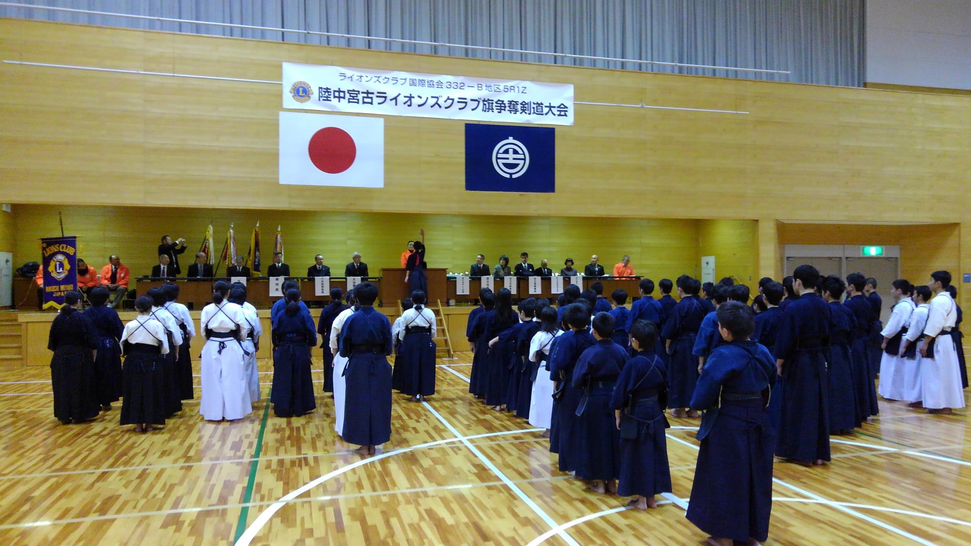 体育館の中で剣道着を着た選手たちが整列している写真
