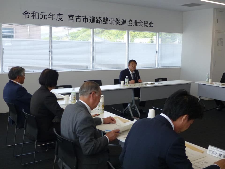 「令和元年度 宮古市道路整備促進協議会総会」と書かれた横幕が天井下の壁に貼られた室内で、参加者が自席に着席し、ガラス窓側の席に座っている市長が話をしている総会の様子の写真