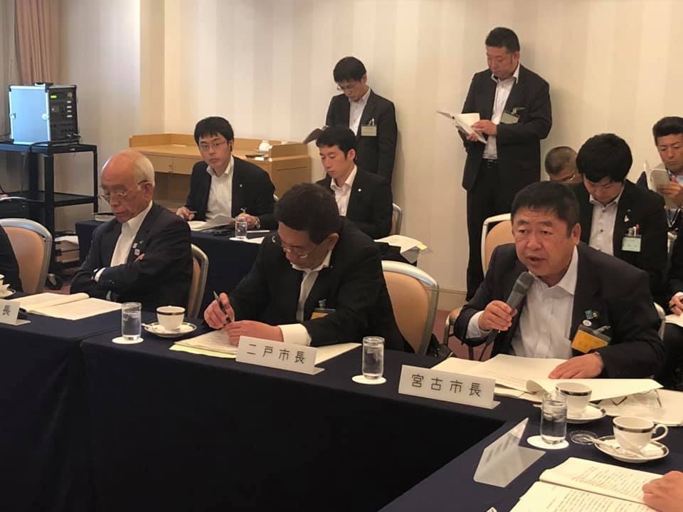 東北地方の市長が参加した「東北市長会総会・分科会」の会場で、自席に座って右手にマイクを持ち話をしている市長の写真