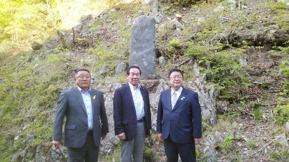 山腹に設置された大津波記念碑の前で、東日本大震災復興加速化本部の額賀福志郎本部長と関係者の男性、市長が並んで立っている写真