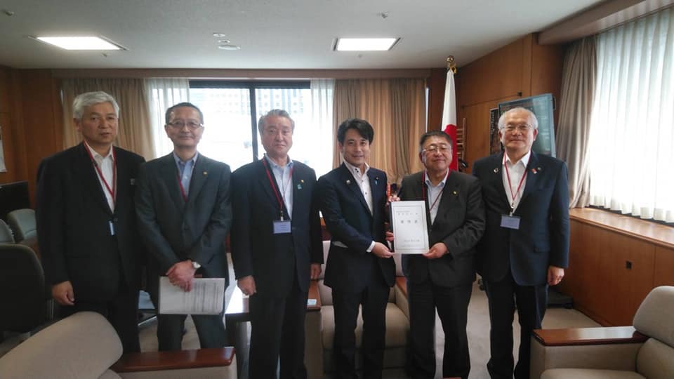 右から2番目と3番目の男性が要望書を持ち市長と関係者の男性5名が横一列に並んでいる記念写真
