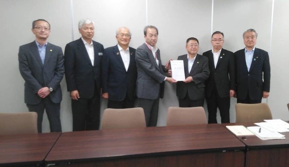 要望書を一緒に持つ市長と男性1名を中心に、関係者の男性5名が横一列に並ぶ記念写真