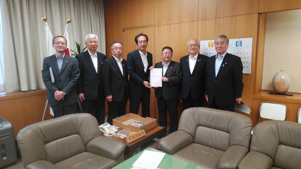 要望書を一緒に持つ市長と男性1名を中心に、関係者の男性5名が横一列に並ぶ記念写真