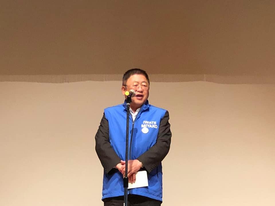 青色のベストを着て、スタンドマイクに向かい話をする市長の写真