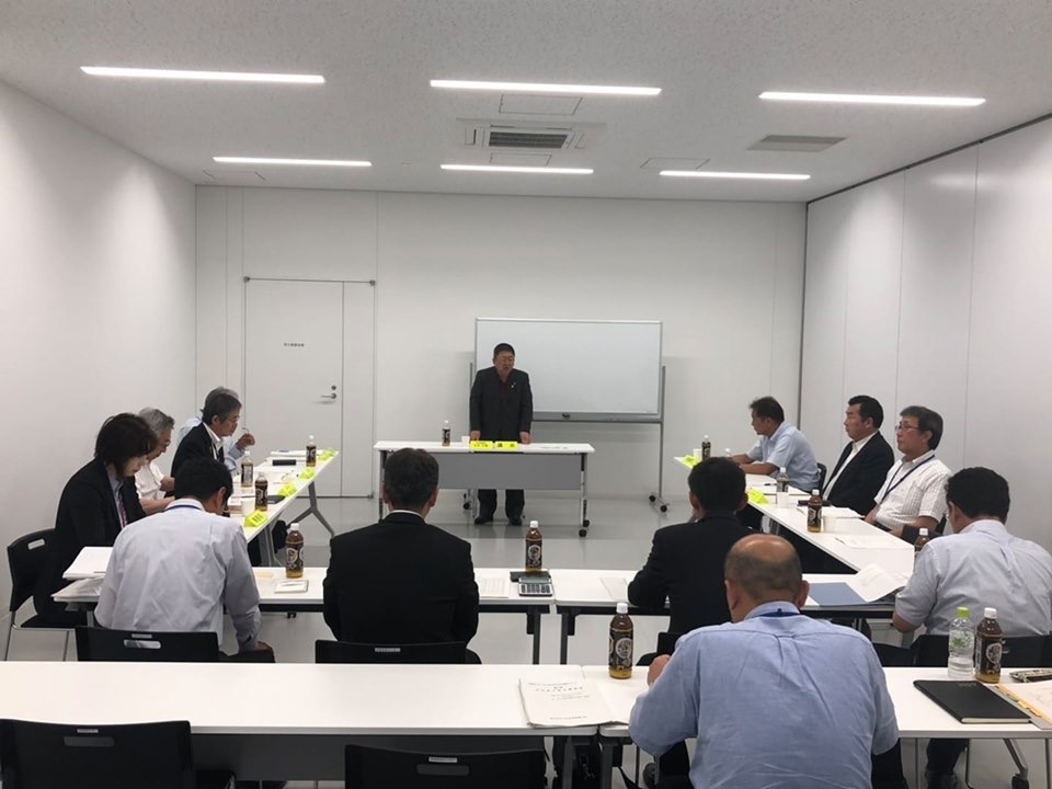 コの字型に並べられたテーブルの席に着く関係者の方々と、前方に置かれたホワイトボードの前に立ち話をする様子の市長の写真