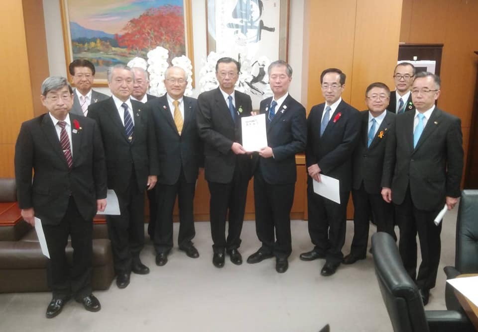 要望書を一緒に持つ2名の男性を中心に、市長と8名の関係者の男性が並んでいる記念写真