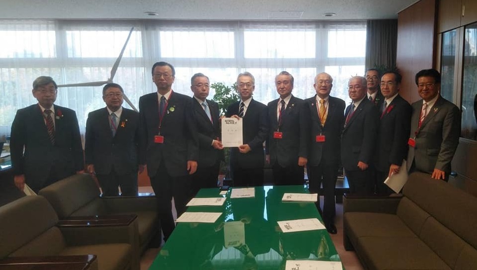 要望書を一緒に持つ2名の男性を中心に、市長と8名の関係者の男性が並んでいる記念写真