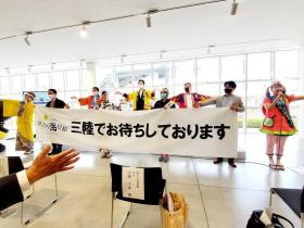 会場内でPRイベントをする方々が三陸でお待ちしておりますと書かれた横断幕を 広げている写真