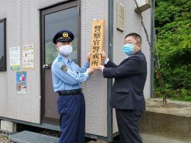浄土ヶ浜海水浴場の建物の前で警察官警戒所と書かれた看板を警察官と市長が持っている写真