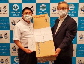 熨斗がついた長方形の段ボール箱を一緒に持つ市長と男性の記念写真