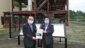 津波遺構「たろう観光ホテル」の前で要望書を一緒に持つ市長と男性の写真