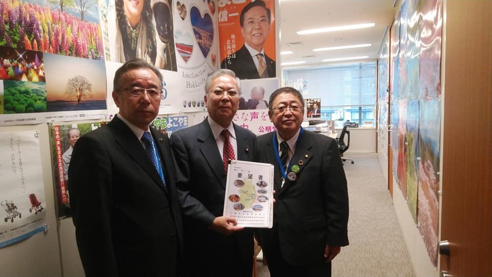 要望書を両手で持つ男性を中心に、市長と男性1名が並んでいる記念写真