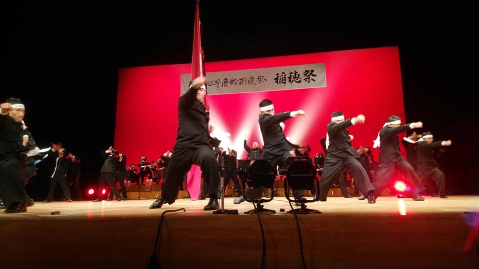 赤いライトが照らされた舞台上で、演技を披露する早稲田大学応援部の方々の写真