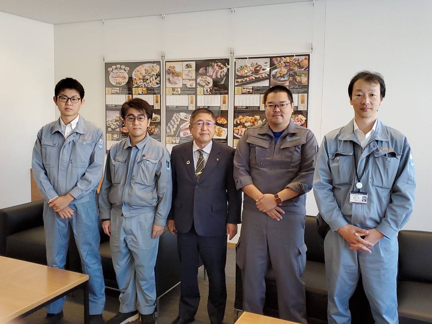 グレーの作業服を着た4名の応援職員の方と市長が写る記念写真