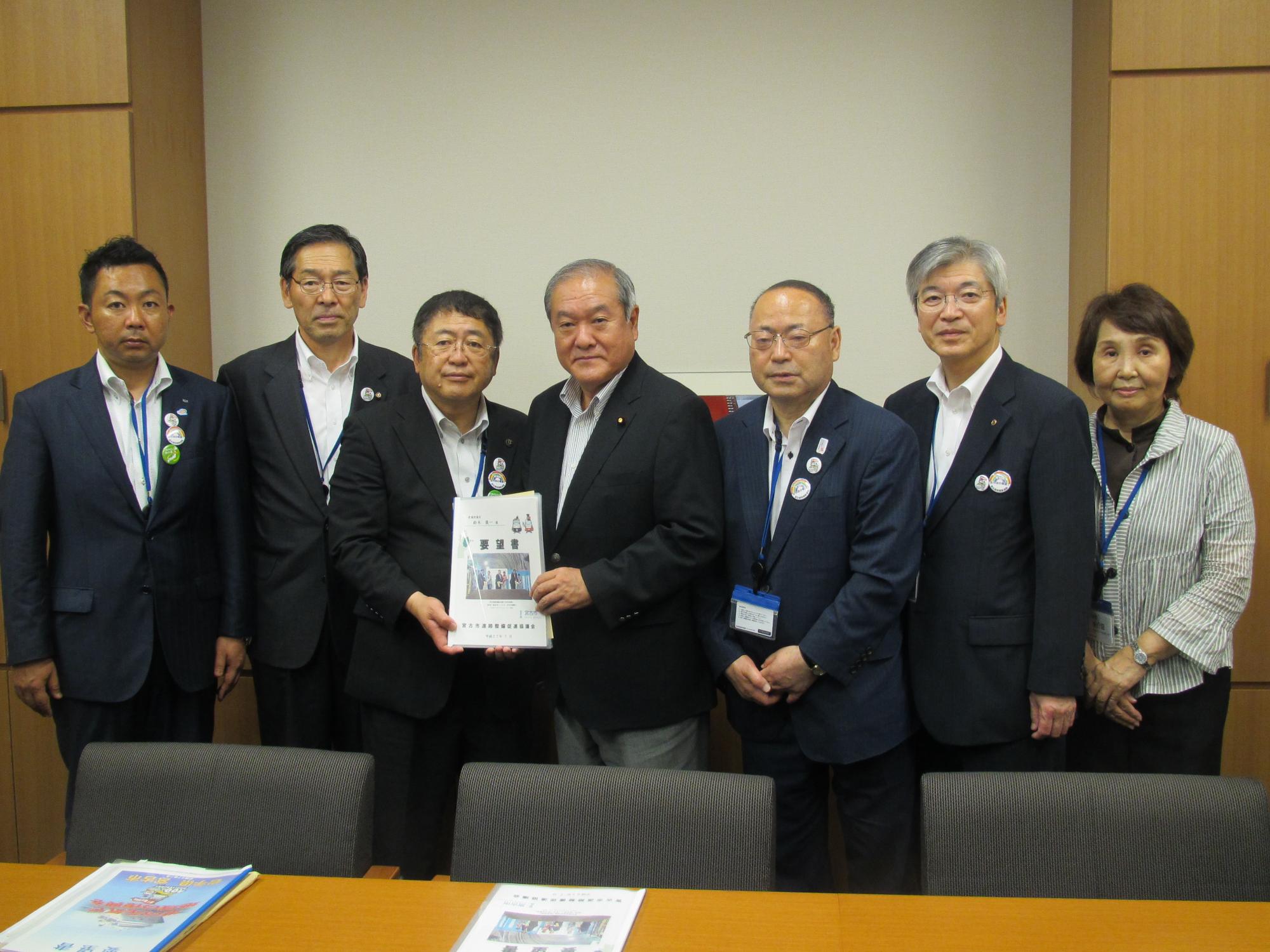 要望書を一緒に持つ市長と男性を中心に、男性4名、女性1名が横一列に並んでいる記念写真
