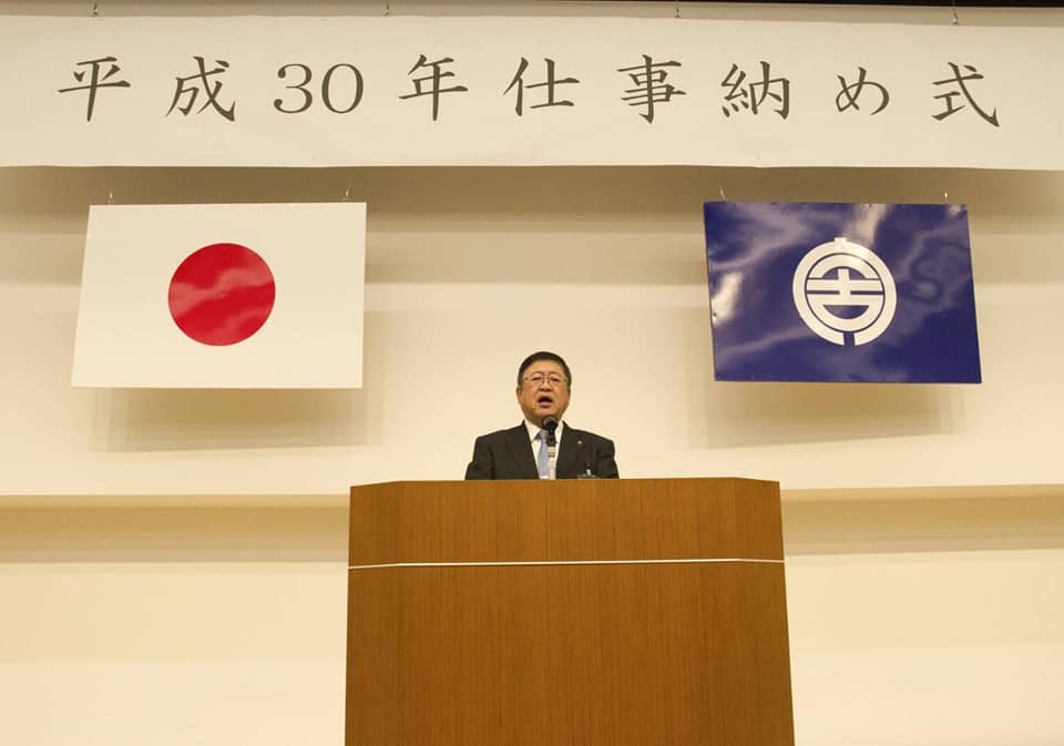 「平成30年仕事納め式」と書かれた横断幕と日本国旗、宮古市の市町村旗が掲げられた会場に置かれた演台で話をする様子の市長の写真