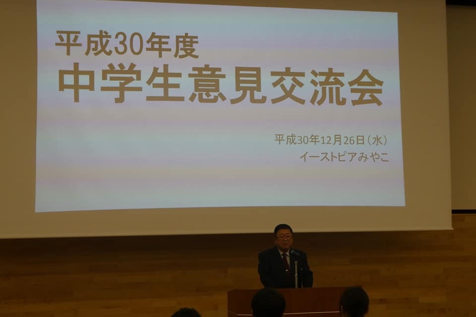 「平成30年度中学生意見交流会」と書かれたスクリーンの前で、演台に置かれたマイクに向かい話をする様子の市長の写真