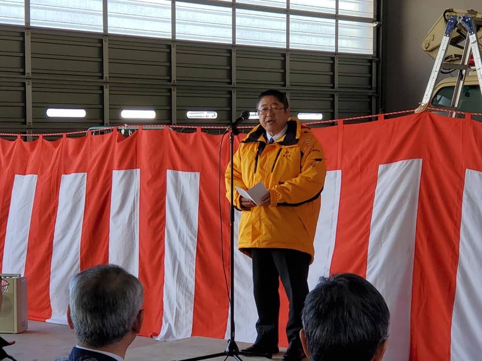 紅白幕の前で台の上に立ちスタンドマイクに向かい話をする様子の市長の写真