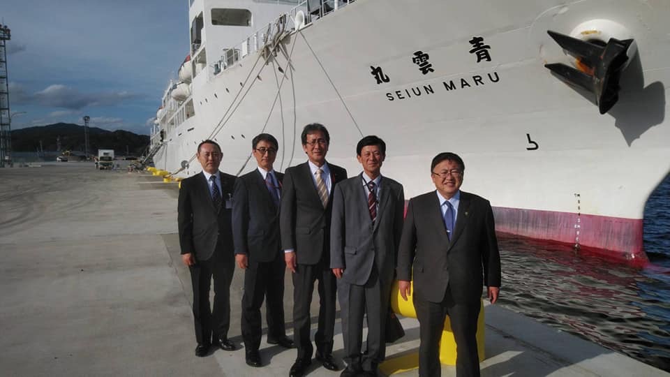 停泊する青雲丸の横で立って記念撮影をする様子の市長と4名のスーツを着た男性の写真