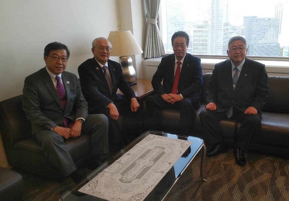 L字型に置かれた革張りの茶色い椅子に、市長と3名のスーツを着た男性が座って記念撮影をしている写真